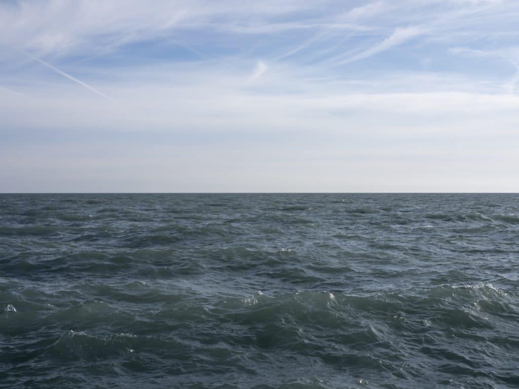 choppy lake water moves under gauzy blue skies with thin clouds