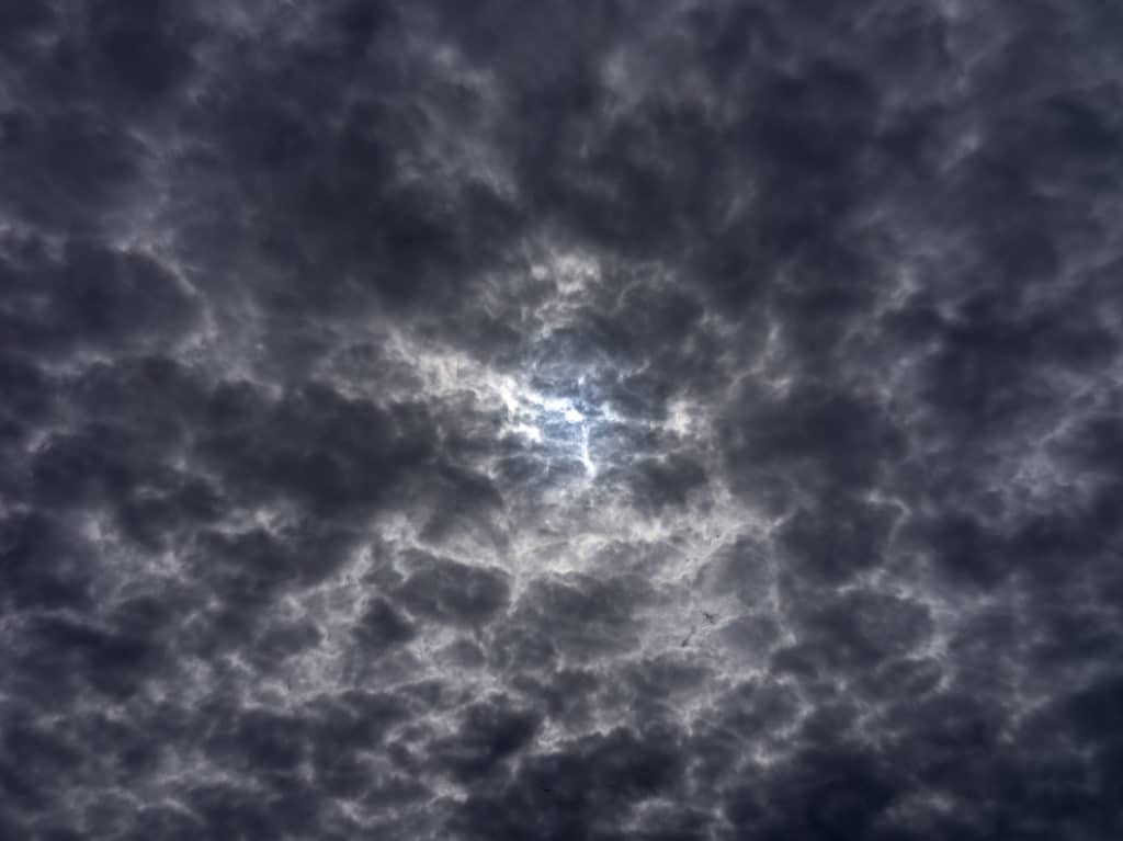 Closer to the Sun (3) features the sky above Lake Michigan in a photograph that captures the moment storms begin to form and threaten the lake