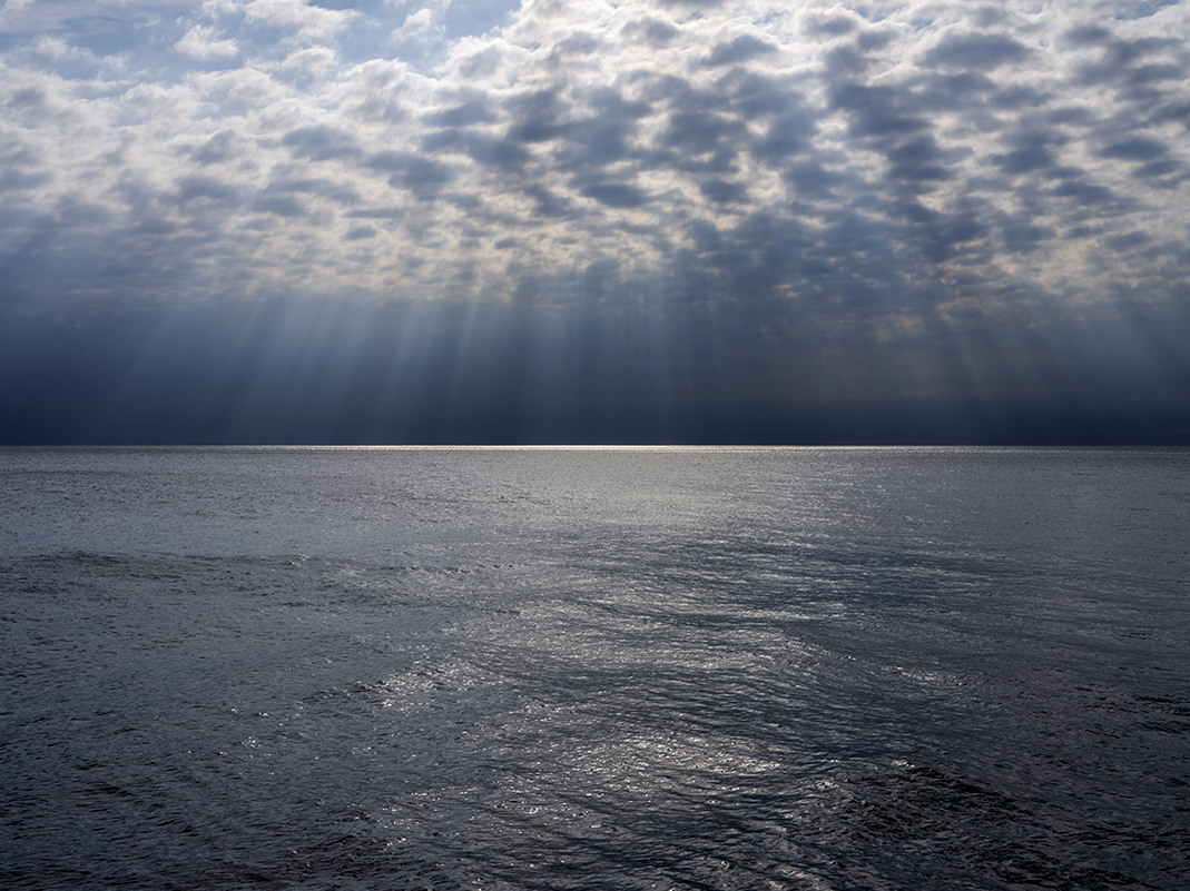 Dappled sunlight strikes the surface of Lake Michigan far from shore. Creating a silver slash and bifurcating the landscape.