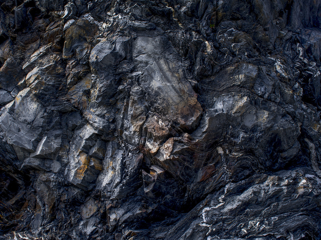 A large rock face, composed of blueschist creates a topography of color and texture that fills this photograph, Lost Coast XV, California landscape photographs. There is a tension in these layers of alternating color created from immense pressure.