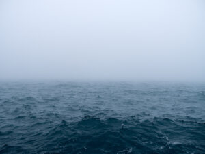 The larger landscape has completely vanished. The waters are choppy, moving quickly and crashing into the wall I stand on. Storms will arrive. But for now, everything is covered in fog. Giving the feeling, although an illusion, that I am alone with the lake.