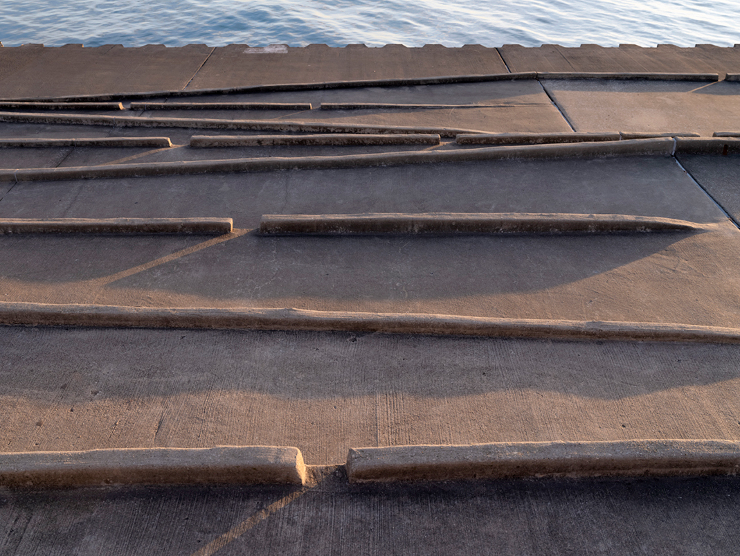 A series of gently sloping ramps make their way down to the serrated edge of the lake wall on Lake Michigan. Concrete and steel hold the lake back in many areas where city and water meet.