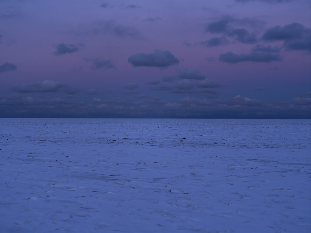 First light is just arriving to an ice covered Lake Michigan as winter sets in. Purple tones, almost unreal are reminiscent of the iridescenct colors that flash from butterfly wings. The clouds are perched in the sky above, frozen in place. I’m alone this morning. A rarity on the lake during summer months. However when winter comes, fewer and fewer people make their way to the lakefront. The stillness of winter on the lake is remarkable and something I look forward to each year.