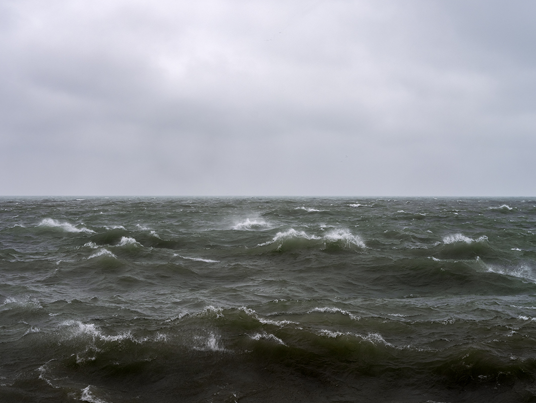 Lake Michigan is awake at dawn with choppy waves on a heavily overcast day. The wind is whipping around me as I photograph on this morning.