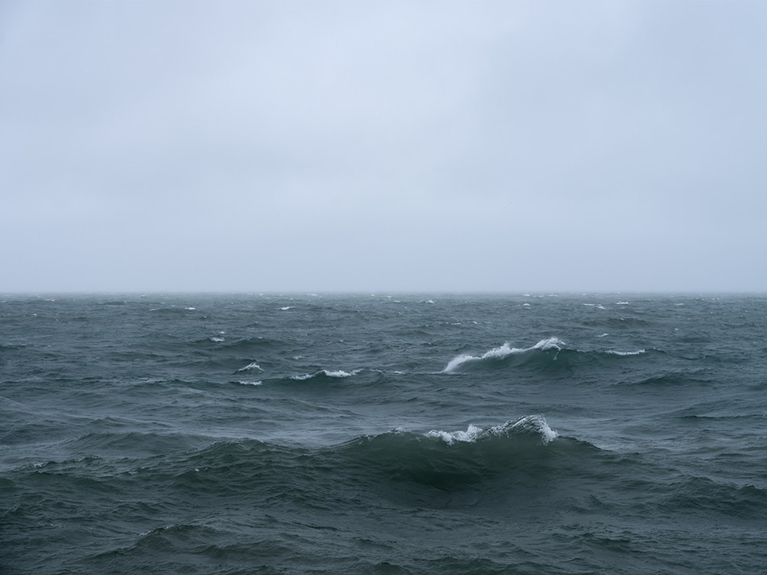 Waves crash and disappear in rhythm with one another near the lake wall on Lake Michigan. It's early May of 2022 and it's a punishing day on the lake. Cold wet weather along with heavy winds bring a clarity to the start of my day.