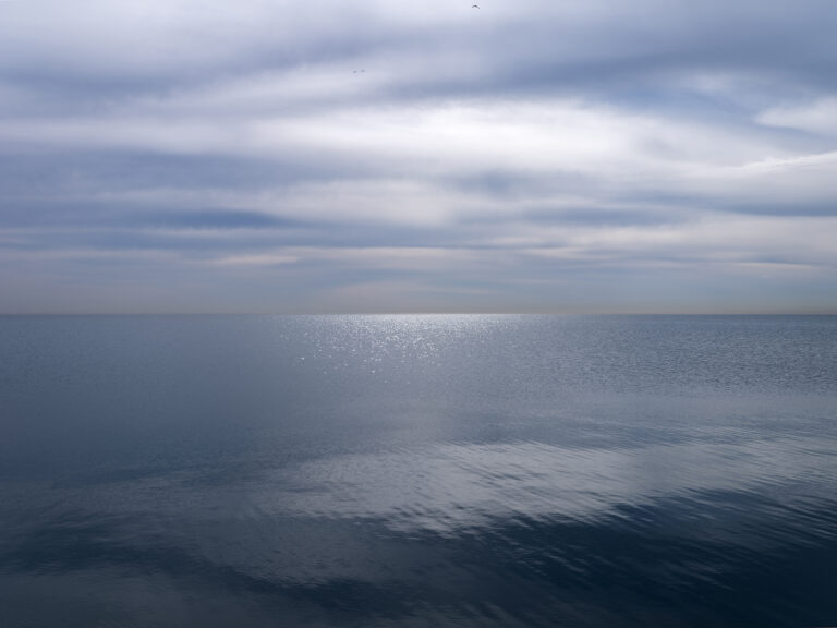 Gentle morning on the lake as sky and water sit motionless in this mid-May photograph from the Lake Series by Lincoln Schatz.