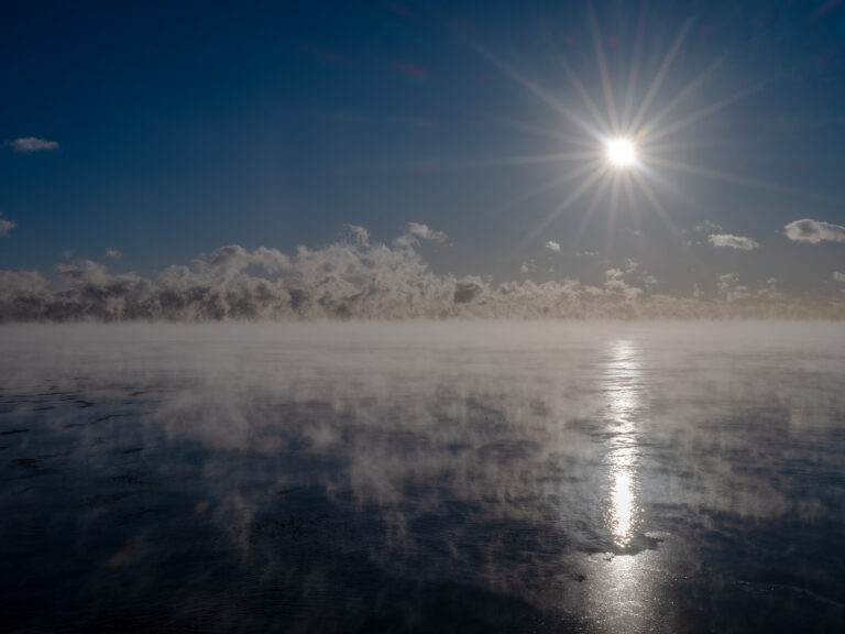 The sun bursts forth from dark skies over a steamy Lake Michigan in this early morning photograph from the Lake Series by Lincoln Schatz.