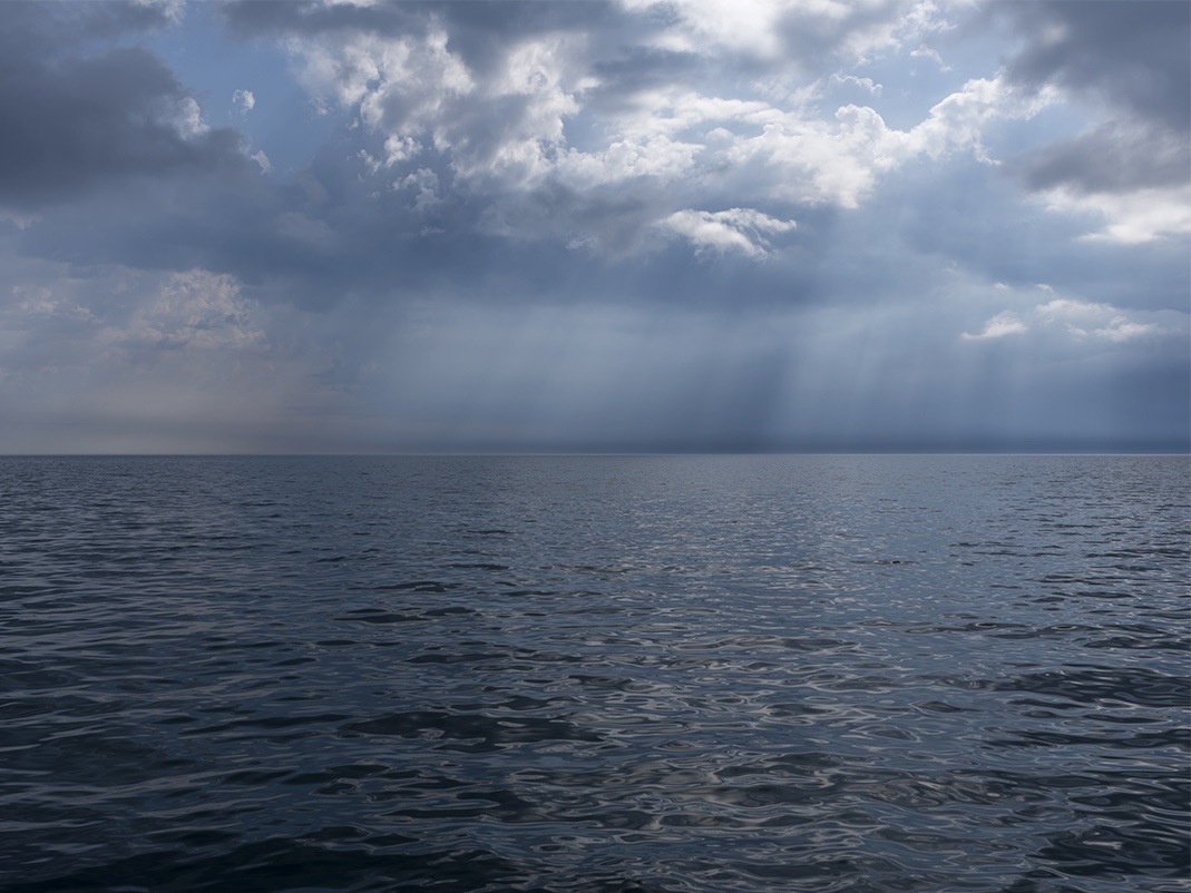 A morning on the lake where the sunlight splits clouds apart, dramatically slashing and illuminating the sky while water and light interact to create a dappled surface on Lake Michigan.