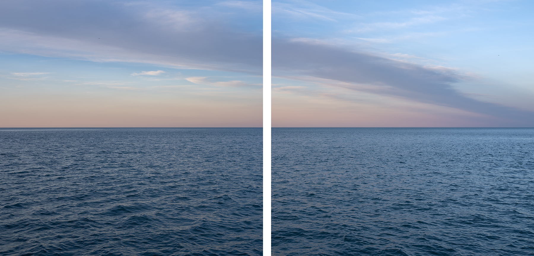 A diagonal of soft clouds fill a blue and peach toned sky late in day over Lake Michigan.