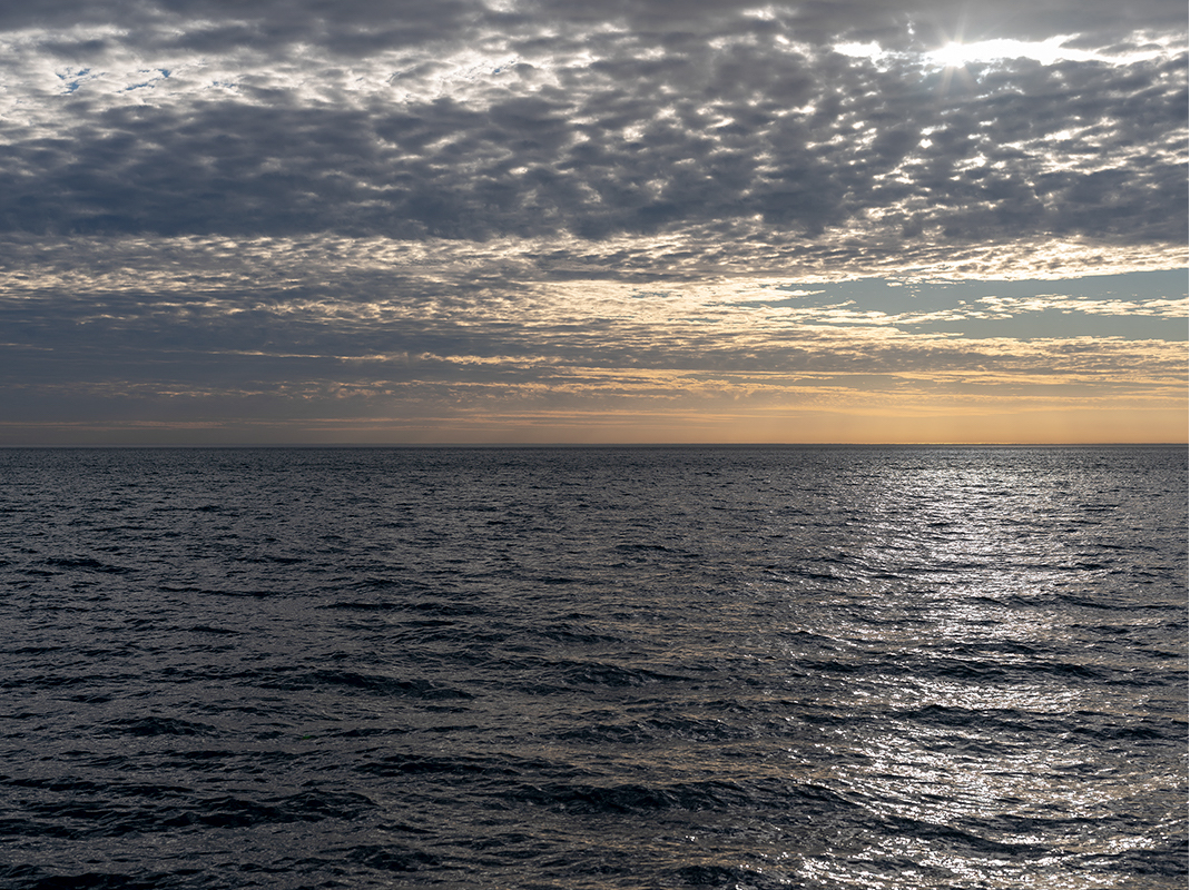 The sun shimmers through clouds rippling across the sky in a photograph from the Lake Series. This is November 9th, 2020 (1).