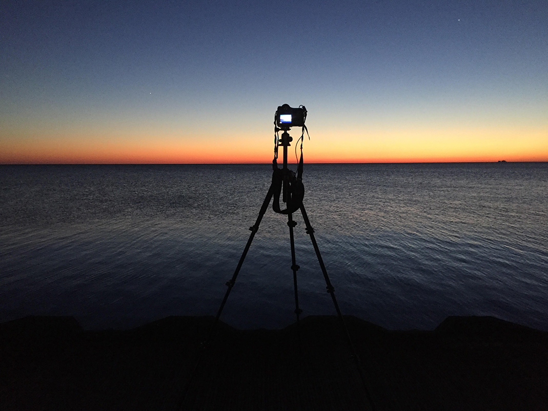 My camera is setup here in early morning on Lake Michigan to photograph for the Lake Series. The first light of day is starting to illuminate the sky over a still quiet lake. Soon the entire landscape will transform before my eyes into brilliant and rich color on a cloudless day on Lake Michigan.