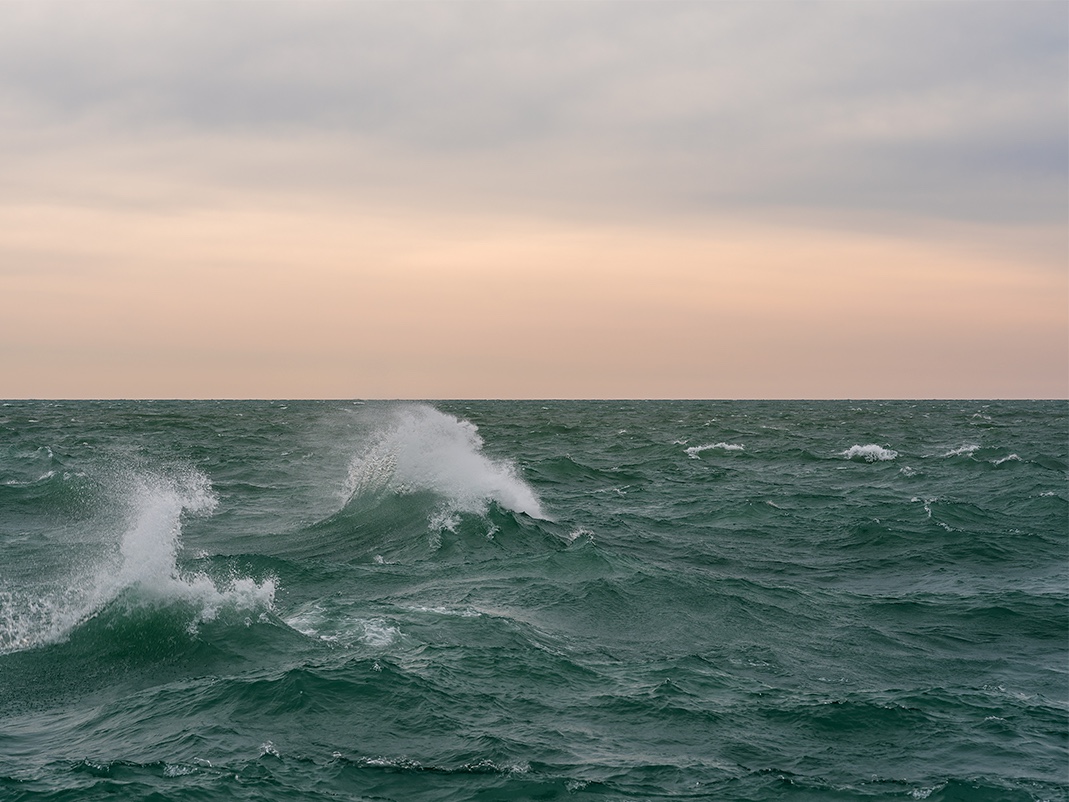 Waves crash on the lake, turned green in stormy weather, as the winds encourage white caps to begin forming in this photograph from the Lake Series. This is the Lake Series, March 5th, 2018 (3).